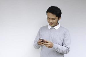 Smart Young asian man is happy and smiling when using smartphone in studio background photo