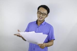 Young Asian Man is smile and happy when looking on paper document. Indonesian man wearing blue shirt. photo