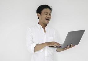 Young asian man is smile and enjoy when working at home with laptop computer. Work from home concept. photo