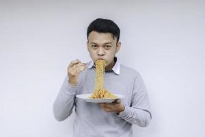 el joven asiático disfruta de los fideos. comer el concepto de almuerzo. foto