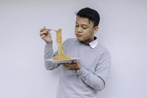 Young Asian man enjoy noodles. Eating lunch concept. photo