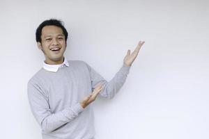 Young Asian man is smile and happy with with hand point on empty space photo