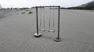 Aerial view of old rope wooden swing on the desert or sandy beach with mountain background photo