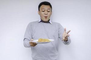 Portrait of Shock and Wow Young Asian man enjoy noodles. Eating lunch concept photo