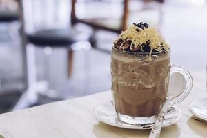 Chocolate Milkshake with chocolate cereals, cheese, and Choco chips in the big clear glass cup. Selective focus close-up on top of it and blurry background. photo