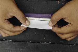 la mano del hombre hace un cigarrillo con herramientas tradicionales rodantes, primer plano de las manos. foto