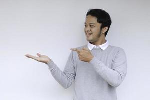 Young Asian man is smile and happy with with hand point on empty space photo