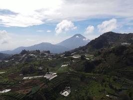 vista aérea de la aldea de dieng en wonosobo con una montaña a su alrededor foto