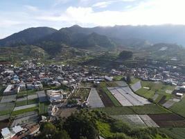 vista aérea de la aldea de dieng en wonosobo con una montaña a su alrededor foto