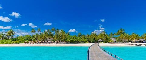 Amazing panorama at Maldives. Luxury resort villas seascape with palm trees, white sand and blue sky. Beautiful summer landscape. Amazing beach background for vacation holiday. Paradise island concept photo