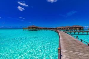 Beautiful beach with water bungalows at Maldives. Maldives island, luxury water villas resort and wooden pier. Beautiful sky and ocean lagoon photo