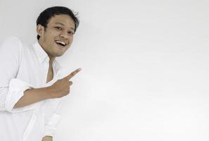 Smile of Young Asian man in white shirt with hand point on empty space photo