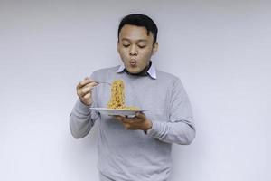 Portrait of Shock and Wow Young Asian man enjoy noodles. Eating lunch concept. photo