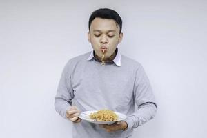 el joven asiático disfruta de los fideos. comer el concepto de almuerzo. foto