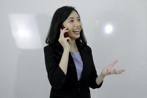 la joven asiática de negocios está feliz usando una computadora portátil y hablando por teléfono foto