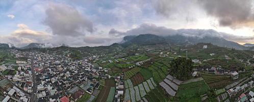 vista aérea de la aldea de dieng en wonosobo con una montaña a su alrededor foto