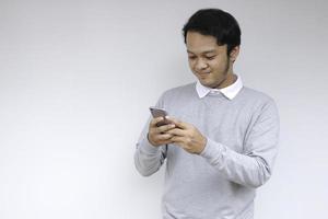 Smart Young asian man is happy and smiling when using smartphone in studio background photo