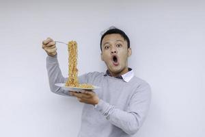 Portrait of Shock and Wow Young Asian man enjoy noodles. Eating lunch concept. photo