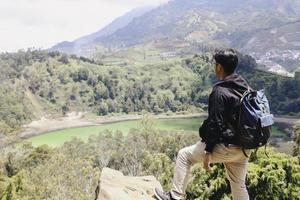 Young asian backpacker man is happy and enjoy traveling in mountain. photo