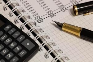 Financial report, a fountain pen with cap and paper with numbers on the table in the office. A paper sheet full of business data. Accounts number on the data paper. Business documents. Close-up photo