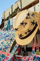 Straw hat with drawings of palm trees in a summer market. Vertical image. photo