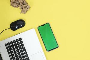 laptop and smartphone on desk isolated on yellow background photo