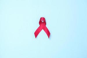 AIDS symbol red ribbon against HIV virus isolated on blue background photo