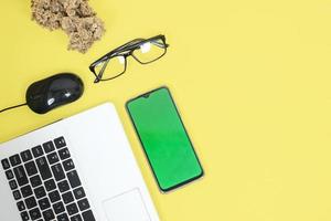 laptop and smartphone on desk isolated on yellow background photo