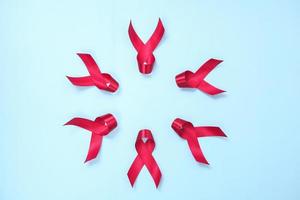 red ribbon composed of symbols of AIDS against HIV virus isolated on blue background photo