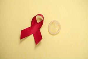 red ribbon and condom symbol against HIV isolated on yellow background photo