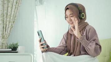 beautiful woman in hijab is greeting via video call happily at home photo