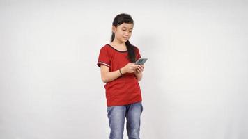 Niña asiática jugando smartphone aislado sobre fondo blanco. foto