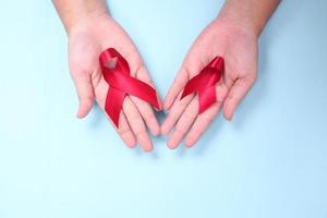 red ribbon in the palm of the symbol against HIV isolated on blue background photo