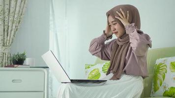 mujer asiática con hiyab se marea con la pantalla de su laptop foto