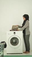 asian woman in hijab folds washed clothes at home photo