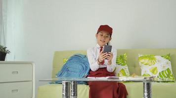 asian elementary school girl looking for ideas on her smartphone for home study material photo