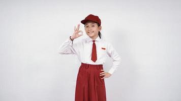 Smiling and okay asian elementary school girl isolated on white background photo