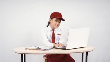 Asian elementary school girl studying online using laptop isolated on white background photo