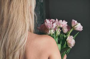 blonde woman holding flowers, view from her back photo