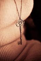 big golden key designed jewelry hanging on female chest photo