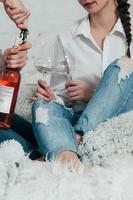 young couple in jeans opens a bottle of rose wine photo