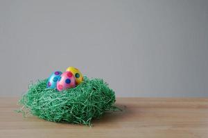 easter eggs in an artificial grass nest on table photo