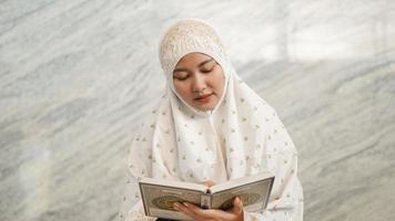 mujer musulmana asiática leyendo el corán en la mezquita foto