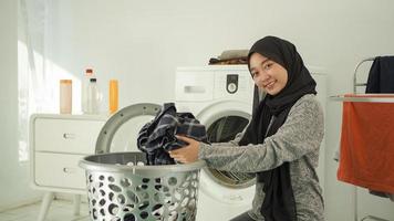 young asian woman picks up dirty clothes to wash at home photo