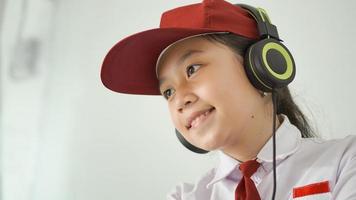 niña asiática de la escuela primaria estudiando en línea en casa felizmente foto