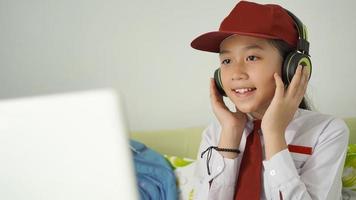 niña asiática de la escuela primaria que estudia en línea escuchando atentamente en casa