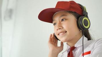 niña asiática de la escuela primaria que estudia en línea en casa escuchando con auriculares foto