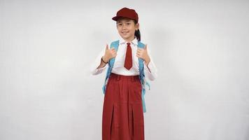 Asian elementary school girl giving two thumbs up isolated on white background photo