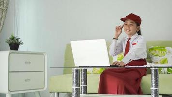 asian elementary school girl finding ideas from laptop at home photo