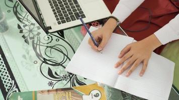 niña de la escuela primaria escribiendo a mano en casa foto